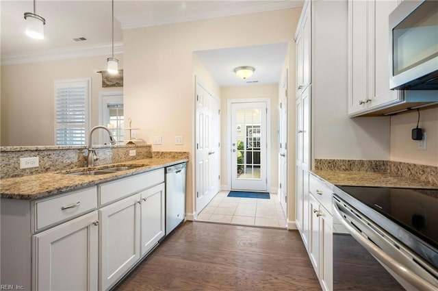 kitchen with sink, hanging light fixtures, stainless steel appliances, light stone countertops, and white cabinets