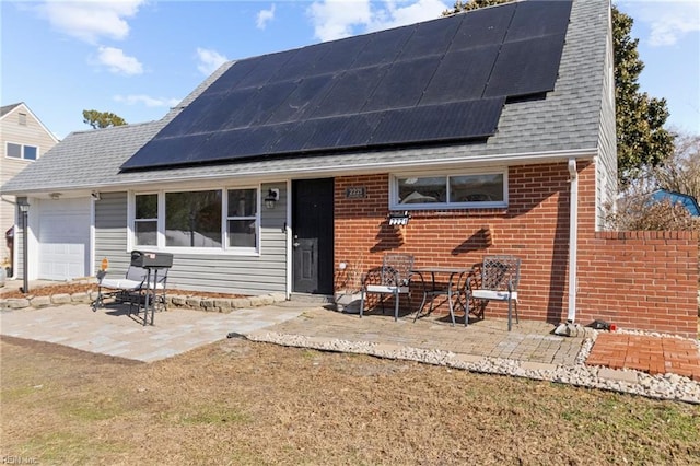 view of front of property featuring a garage, a patio, a front lawn, and solar panels