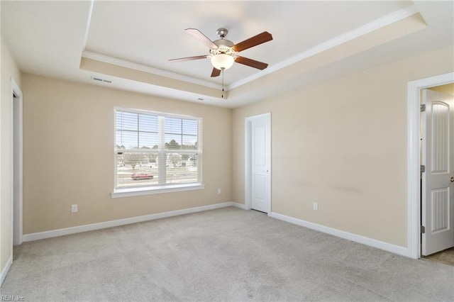 unfurnished bedroom featuring ornamental molding, light colored carpet, a raised ceiling, and ceiling fan