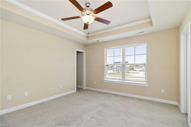 unfurnished room featuring light carpet, a tray ceiling, and crown molding