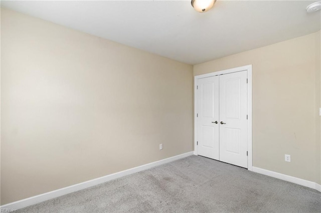 unfurnished bedroom featuring light carpet and a closet