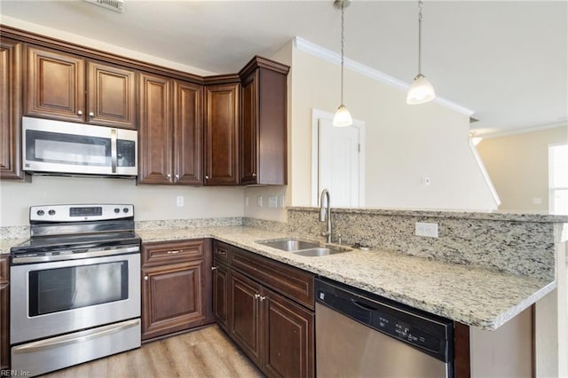 kitchen with sink, hanging light fixtures, ornamental molding, appliances with stainless steel finishes, and light stone countertops