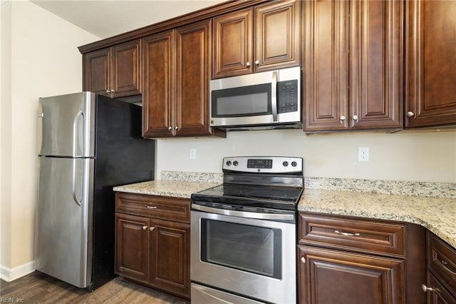 kitchen featuring light stone countertops, appliances with stainless steel finishes, and dark wood-type flooring