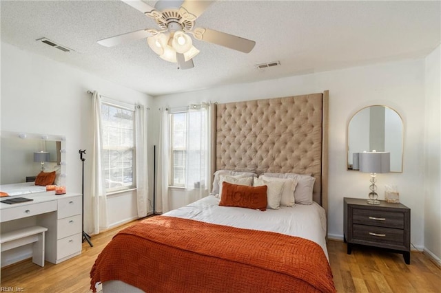 bedroom with a textured ceiling, ceiling fan, and light hardwood / wood-style floors