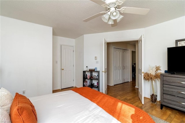 bedroom with a textured ceiling, light hardwood / wood-style floors, and ceiling fan