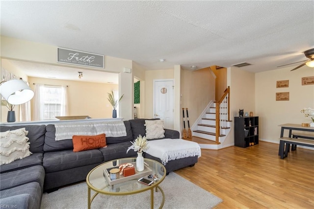 living room featuring ceiling fan, a textured ceiling, and light hardwood / wood-style floors