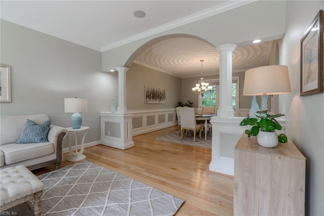 living room with hardwood / wood-style flooring, ornamental molding, decorative columns, and a notable chandelier