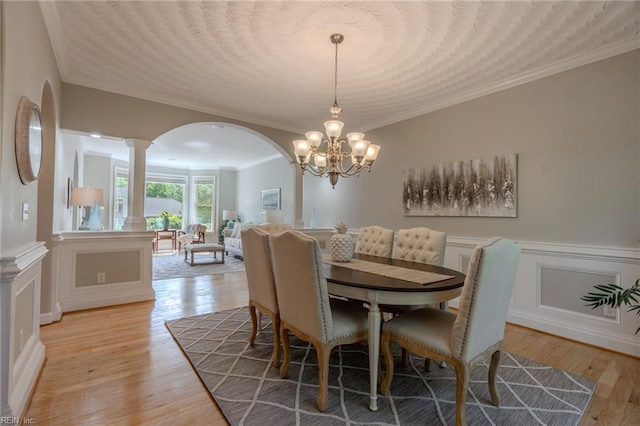 dining area featuring ornamental molding, light hardwood / wood-style floors, and ornate columns