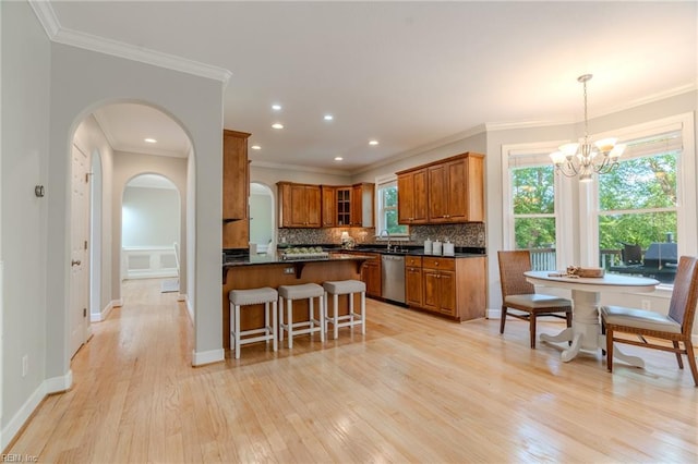 kitchen with tasteful backsplash, hanging light fixtures, light hardwood / wood-style flooring, stainless steel dishwasher, and kitchen peninsula