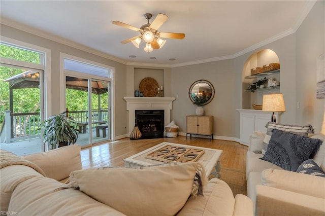 living room with crown molding, ceiling fan, and light wood-type flooring