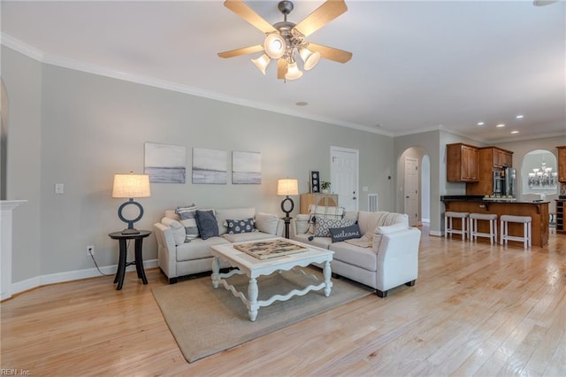 living room with ornamental molding, ceiling fan with notable chandelier, and light hardwood / wood-style flooring