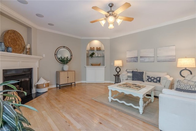 living room featuring hardwood / wood-style floors, crown molding, built in features, and ceiling fan