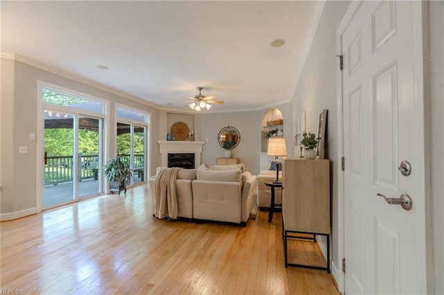 living room featuring crown molding, ceiling fan, and light hardwood / wood-style floors