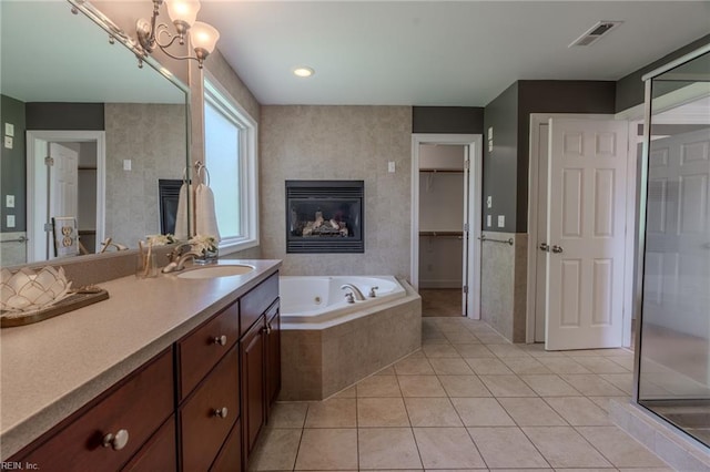 bathroom with a tiled fireplace, vanity, tile patterned floors, and shower with separate bathtub