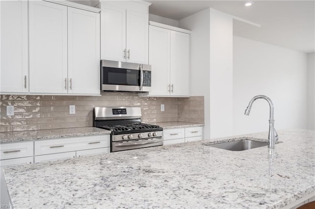 kitchen featuring sink, stainless steel appliances, white cabinets, and light stone countertops