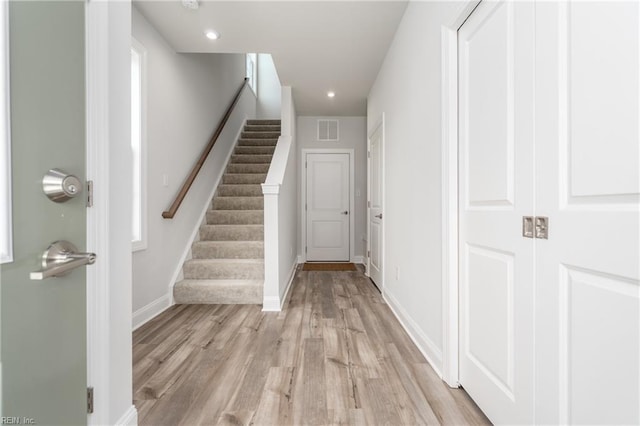 hallway with a healthy amount of sunlight and light hardwood / wood-style floors