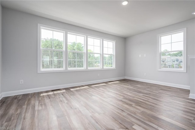 unfurnished room featuring plenty of natural light and hardwood / wood-style floors