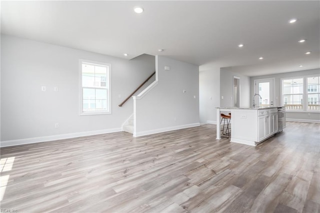 unfurnished living room featuring sink and light wood-type flooring