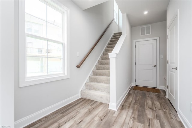 stairs featuring wood-type flooring and a healthy amount of sunlight