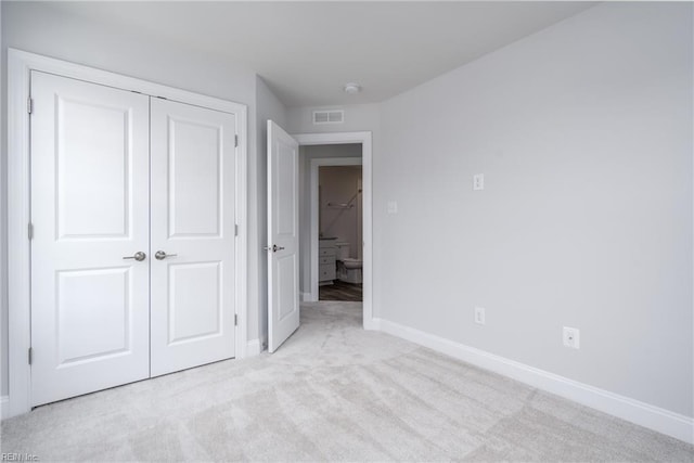 unfurnished bedroom with a closet and light carpet