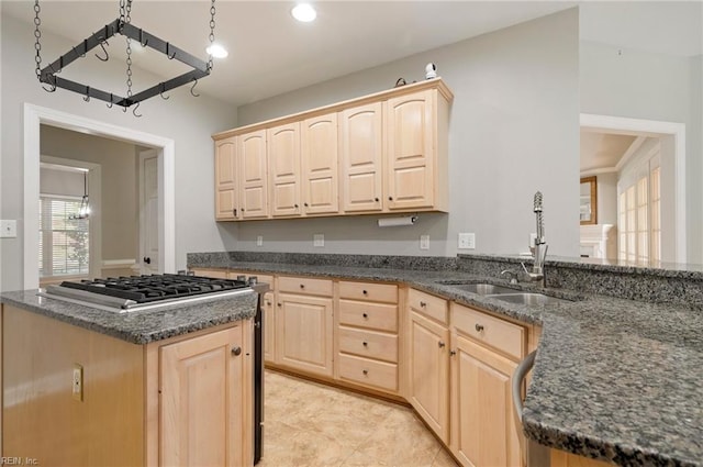 kitchen with stainless steel gas cooktop, light brown cabinetry, sink, and dark stone countertops