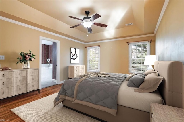 bedroom featuring ornamental molding, dark hardwood / wood-style floors, a raised ceiling, and multiple windows