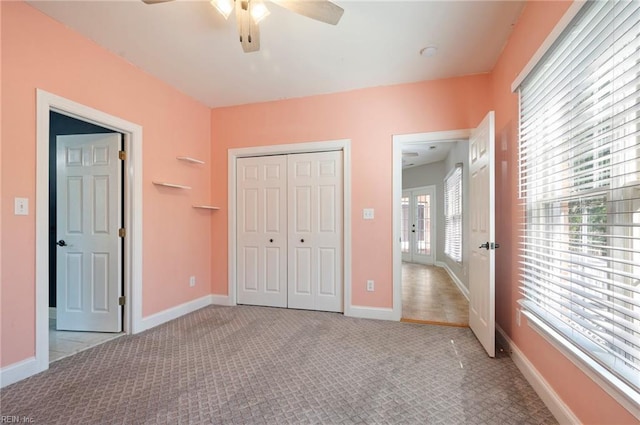 unfurnished bedroom featuring ceiling fan, light colored carpet, and a closet