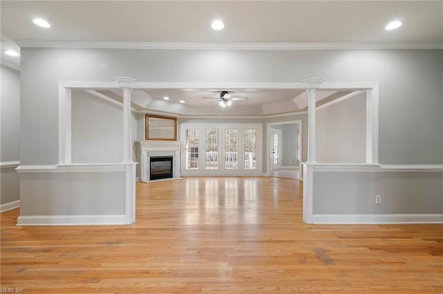 unfurnished living room featuring decorative columns, ornamental molding, ceiling fan, and light wood-type flooring