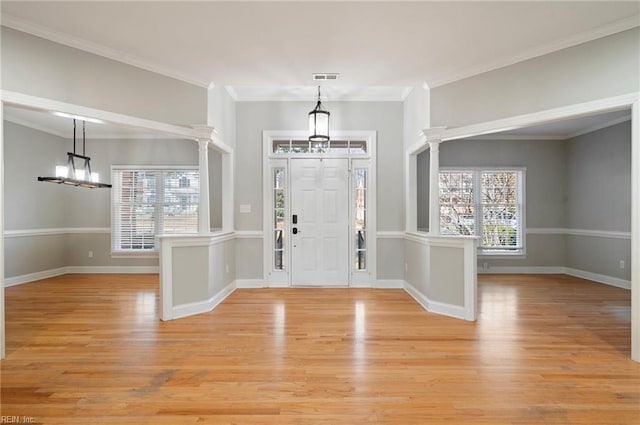 entrance foyer with ornamental molding, a notable chandelier, and light wood-type flooring