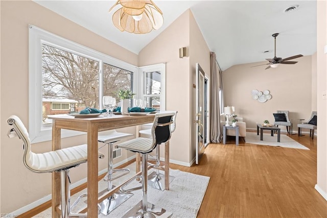 dining space with vaulted ceiling, ceiling fan, and light wood-type flooring