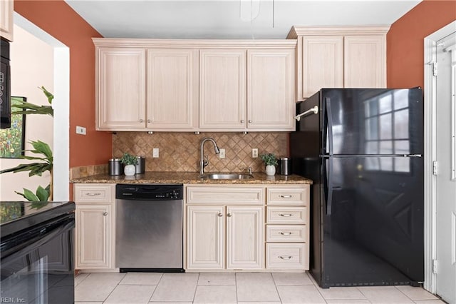 kitchen featuring light tile patterned flooring, sink, light stone counters, black appliances, and backsplash