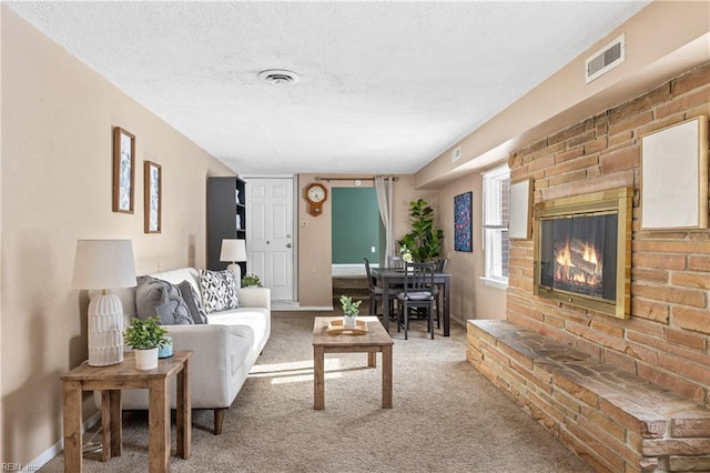 carpeted living room with a brick fireplace and a textured ceiling