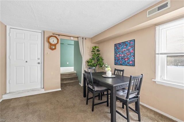 dining area featuring carpet flooring and a textured ceiling