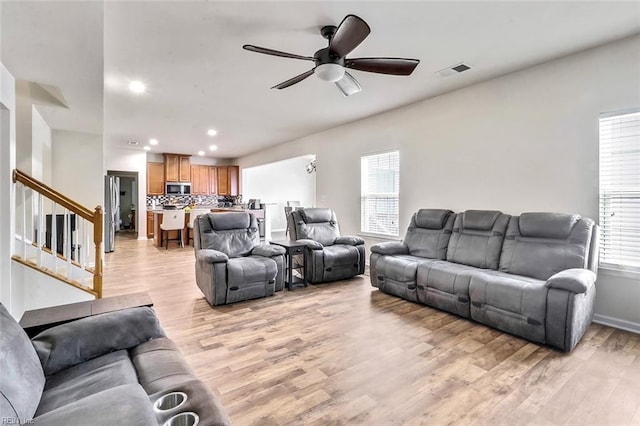 living room with light hardwood / wood-style floors and ceiling fan