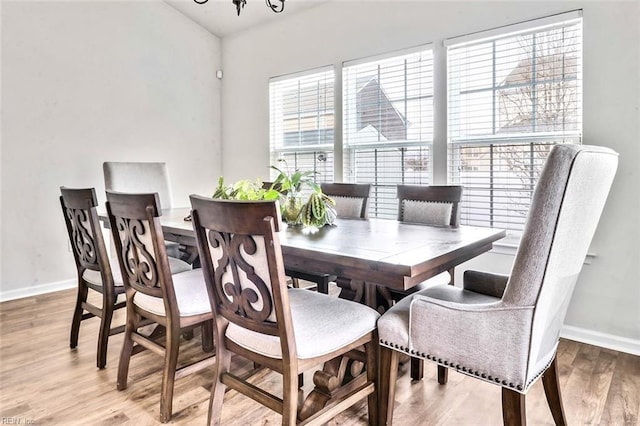 dining room with wood-type flooring, lofted ceiling, and a chandelier