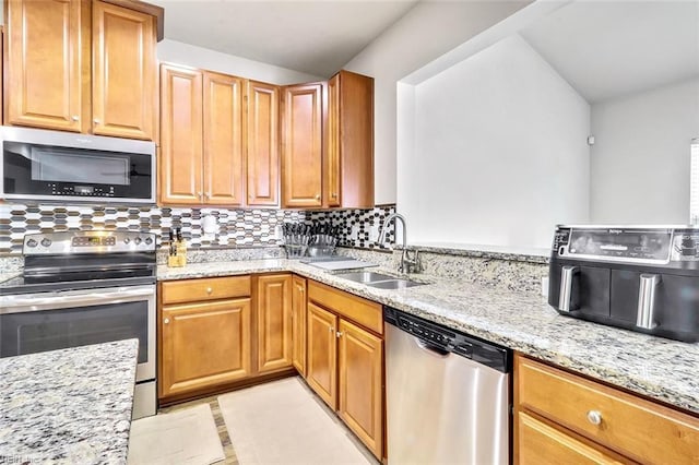 kitchen featuring light tile patterned flooring, appliances with stainless steel finishes, tasteful backsplash, sink, and light stone countertops