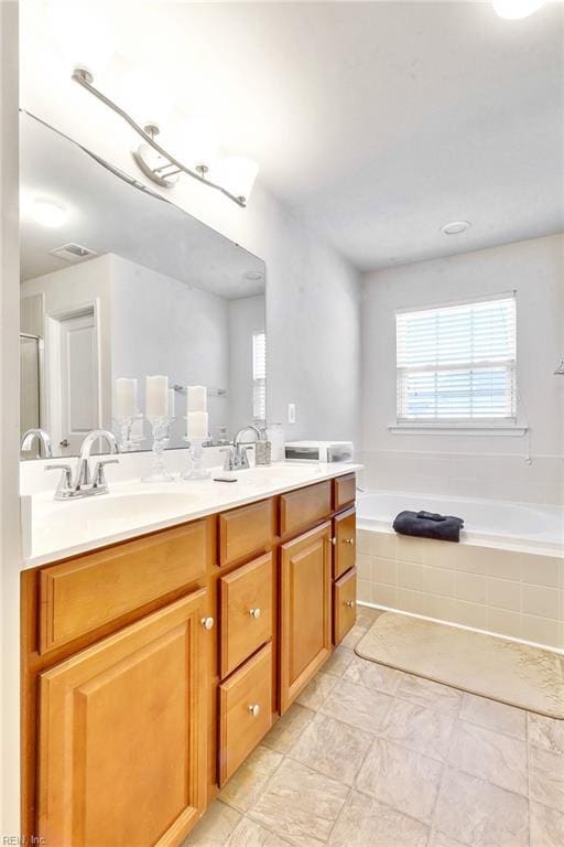 bathroom featuring vanity and tiled bath