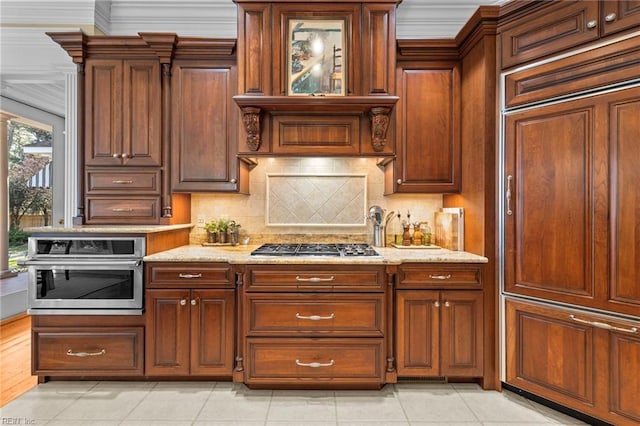 kitchen with decorative backsplash, light tile patterned floors, stainless steel appliances, crown molding, and light stone countertops