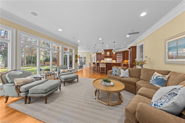 living room with ornamental molding and light hardwood / wood-style flooring