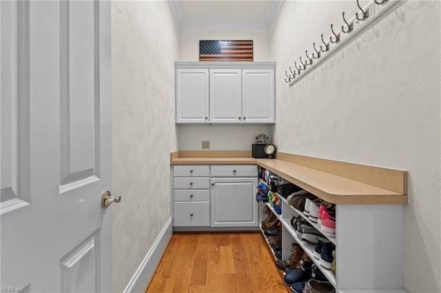 laundry area with ornamental molding and light wood-type flooring