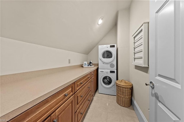 laundry room with cabinets, stacked washer / dryer, and light tile patterned floors