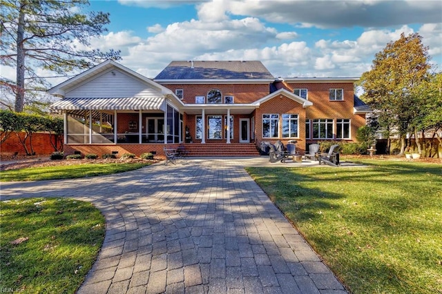 view of front facade with a patio, a sunroom, and a front lawn