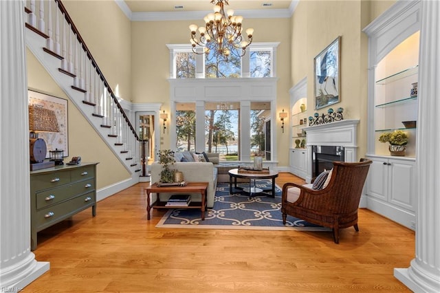 living area featuring an inviting chandelier, crown molding, and light wood-type flooring