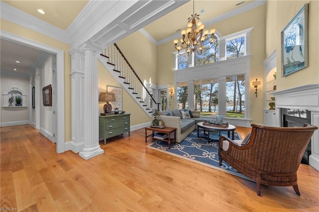 interior space featuring a notable chandelier, a fireplace, decorative columns, and light wood-type flooring