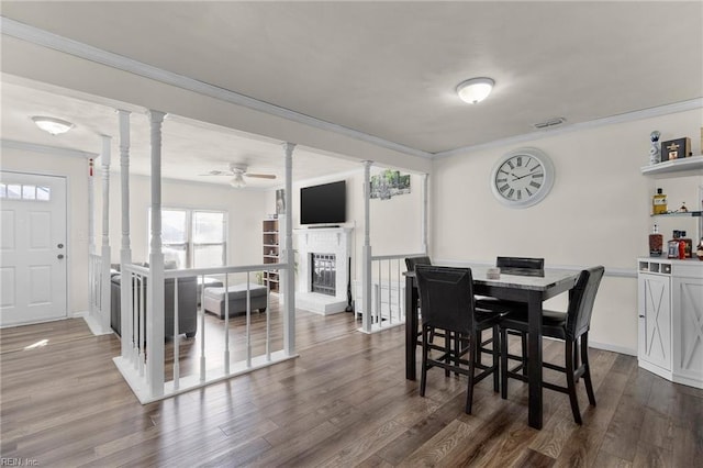 dining room featuring decorative columns, crown molding, and hardwood / wood-style floors