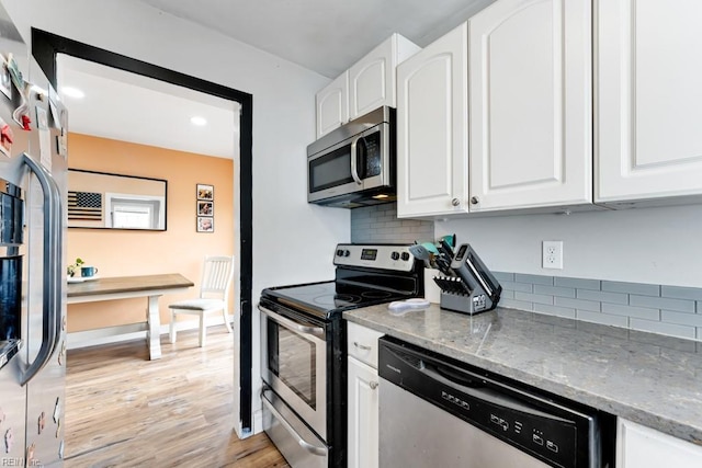 kitchen with stainless steel appliances, light stone countertops, light wood-type flooring, and white cabinets