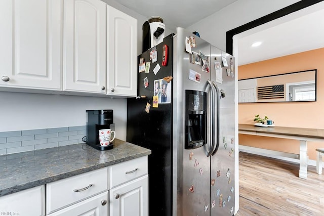 kitchen with white cabinetry, stainless steel fridge with ice dispenser, light hardwood / wood-style flooring, and dark stone countertops