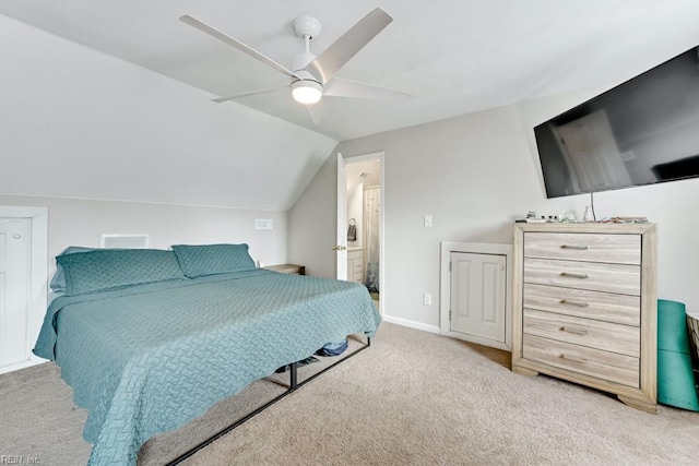 bedroom with light carpet, vaulted ceiling, ceiling fan, and ensuite bathroom