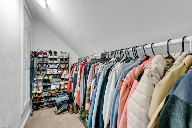 walk in closet with vaulted ceiling and carpet flooring