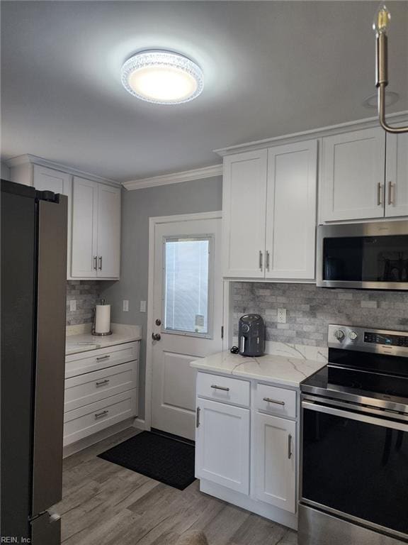 kitchen featuring stainless steel appliances, white cabinets, and backsplash